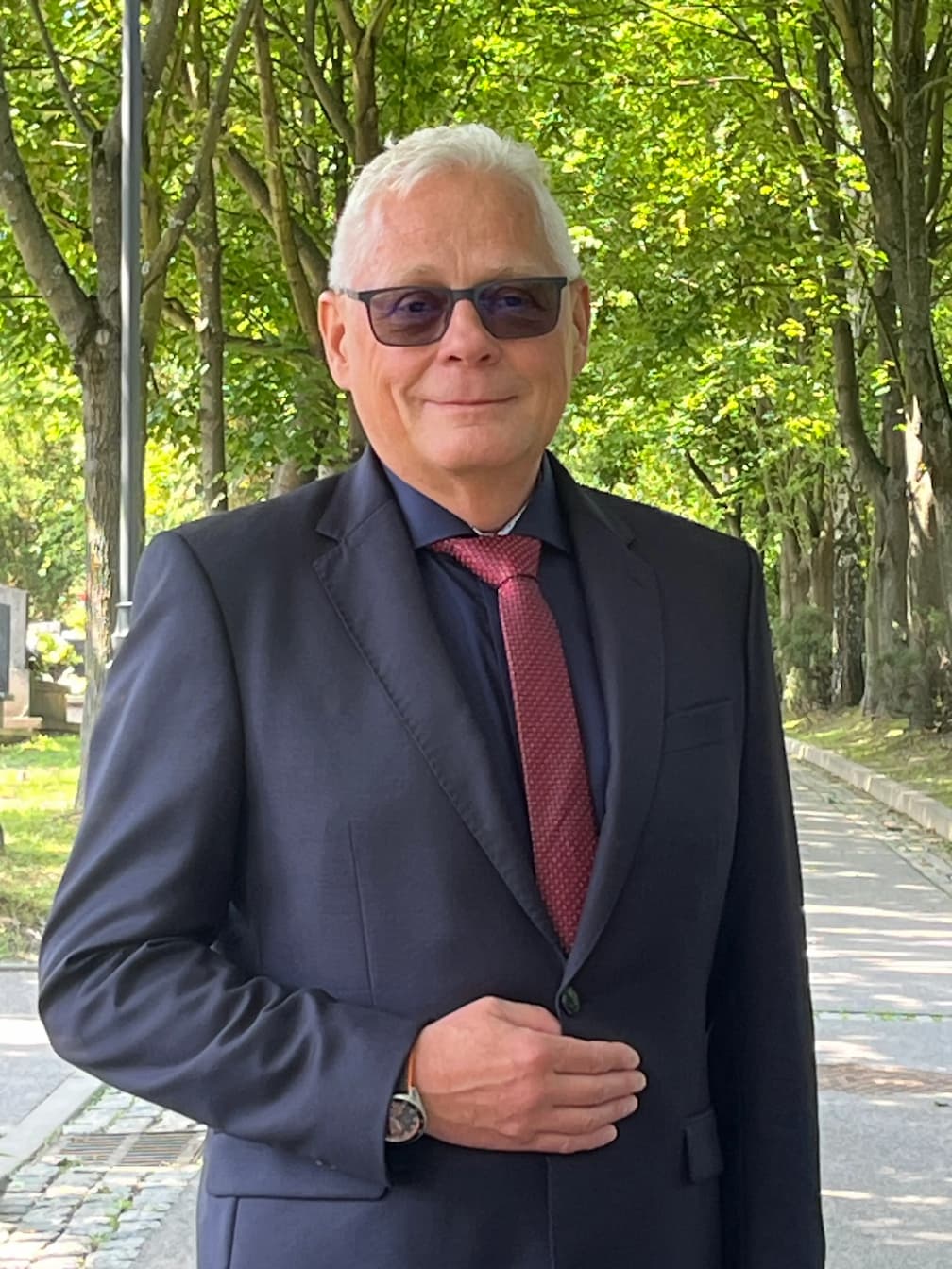 Krzysztof Pikulski, mistrz ceremonii pogrzebowej, na tle alei drzew